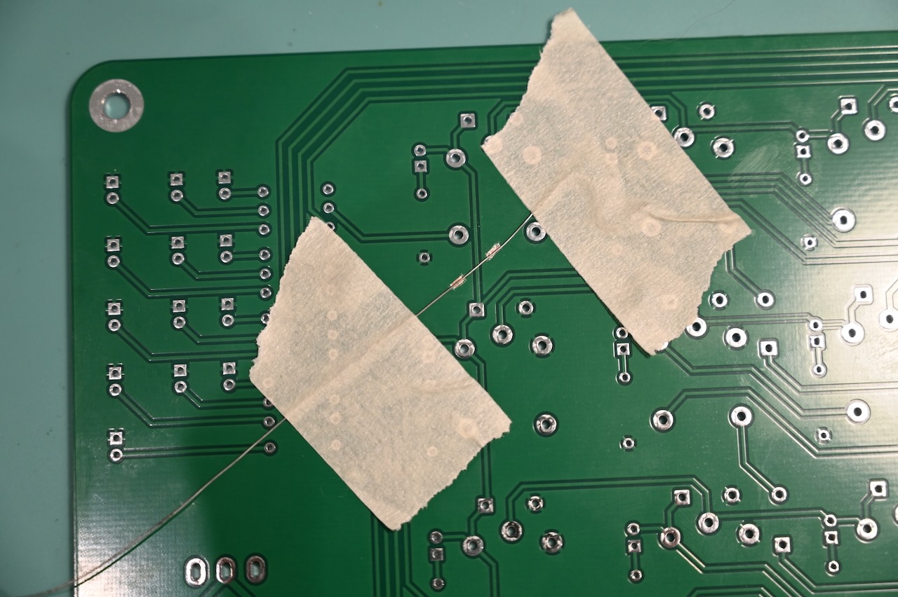 A wire taped to the bottom of a circuit board